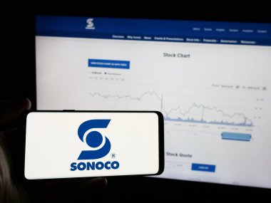 Stuttgart, Almanya - 01-08-2024: ABD ambalaj şirketi Sonoco Products Company 'nin logosunu elinde tutan kişi web sitesi önünde ekranda. Telefon ekranına odaklan.