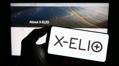 Stuttgart, Almanya - 04-02-2023: Üzerinde İspanyol yenilenebilir enerji şirketi X-ELIO Enerji S.L. logosu bulunan kişi Web sayfasının önünde ekranda. Telefon ekranına odaklan.