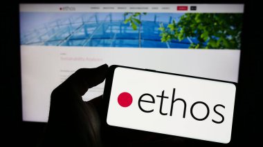 Stuttgart, Almanya - 04-02-2023: İsviçreli finans kurumu Ethos Foundation 'ın logosu web sayfasının önünde ekranda olan cep telefonu sahibi kişi. Telefon ekranına odaklan.