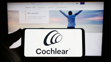 Stuttgart, Almanya - 04-02-2023: Tıbbi teknoloji şirketi Cochlear Limited 'in logosuna sahip akıllı telefon sahibi kişi web sitesinin önünde ekranda. Telefon ekranına odaklan.