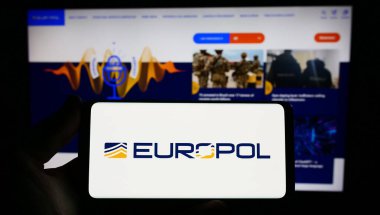Stuttgart, Almanya - 04-02-2023: İnternet sitesi önünde ekranda AB yasa uygulama dairesi Europol 'ün logosuna sahip akıllı telefonu tutan kişi. Telefon ekranına odaklan.
