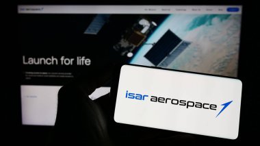 Stuttgart, Almanya - 04-02-2023: Isar Aerospace Technologies GmbH şirketinin logosuna sahip cep telefonu sahibi kişi iş sayfasının önünde ekranda. Telefon ekranına odaklan.