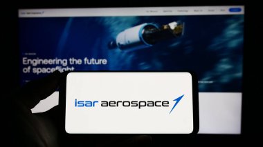 Stuttgart, Almanya - 04-02-2023: Isar Aerospace Technologies GmbH şirketinin logosuna sahip cep telefonu sahibi kişi iş sayfasının önünde ekranda. Telefon ekranına odaklan.