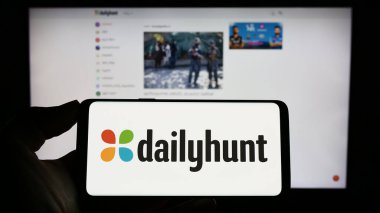Stuttgart, Almanya - 04-02-2023: İnternet sayfası önünde Dailyhunt adlı Hint haber toplama platformunun logosuna sahip kişi. Telefon ekranına odaklan.
