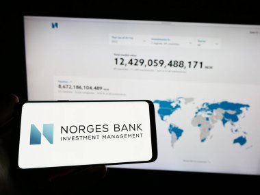 Stuttgart, Almanya - 04-02-2023: Web sitesi önünde Norges Bank Investment Management (NBIM) logosuna sahip akıllı telefon sahibi kişi. Telefon ekranına odaklan.
