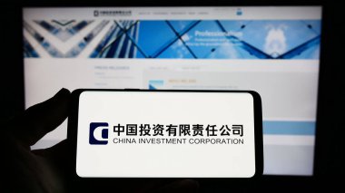 Stuttgart, Almanya - 04-02-2023: İnternet sitesi önünde ekranda Çin Yatırım Şirketi 'nin (CIC) logosuna sahip akıllı telefonu tutan kişi. Telefon ekranına odaklan.