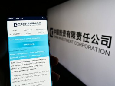 Stuttgart, Almanya - 04-02-2023: Çin Yatırım Şirketi 'nin (CIC) web sayfası logonun önünde duran kişi. Telefon ekranının merkezine odaklan.