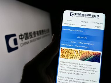 Stuttgart, Almanya - 04-02-2023: Çin Yatırım Şirketi 'nin (CIC) web sitesi ile logo önünde akıllı telefonu elinde tutan kişi. Telefon ekranının merkezine odaklan.