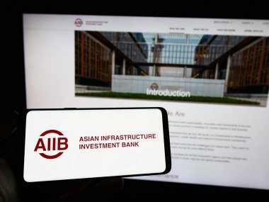 Stuttgart, Almanya - 04-02-2023: Web sayfasının önünde Asya Altyapı Yatırım Bankası (AIIB) logosu olan cep telefonu sahibi kişi. Telefon ekranına odaklan.