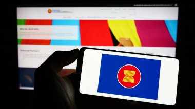 Stuttgart, Germany - 04-02-2023: Person holding cellphone with logo of Association of Southeast Asian Nations (ASEAN) on screen in front of webpage. Focus on phone display. clipart