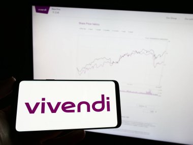 Stuttgart, Almanya - 04-04-2023: Fransız kitle iletişim kuruluşu Vivendi SE 'nin logosuyla cep telefonu sahibi kişi iş sayfasının önünde ekranda. Telefon ekranına odaklan.
