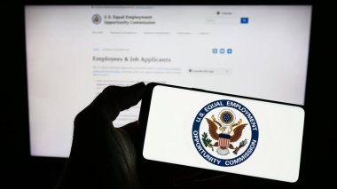 Stuttgart, Almanya - 04-04-2023: İnternet sitesi önünde üzerinde Eşit İstihdam Fırsatı Komisyonu (EEOC) logosu bulunan akıllı telefon sahibi kişi. Telefon ekranına odaklan.