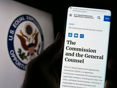 Stuttgart, Almanya - 04-04-2023: Eşit İstihdam Fırsatı Komisyonu 'nun (EEOC) web sayfası logolu cep telefonu tutan kişi. Telefon ekranının merkezine odaklan.