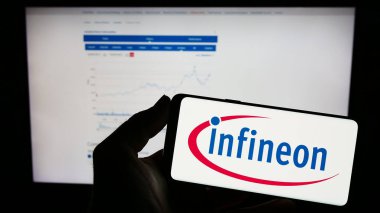 Stuttgart, Almanya - 04-16-2023: Yarı iletken AG şirketinin logosuna sahip cep telefonu sahibi kişi web sayfasının önünde ekranda. Telefon ekranına odaklan.