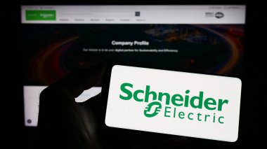 Stuttgart, Almanya - 04-16-2023: İnternet sitesinin önünde ekranda Schneider Electric SE 'nin logosunu taşıyan kişi. Telefon ekranına odaklan.