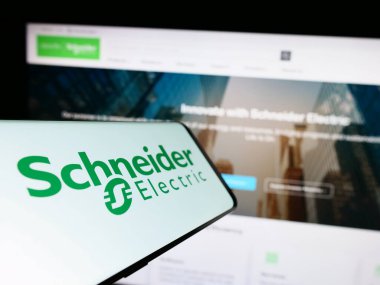 Stuttgart, Almanya - 04-16-2023: Fransız Schneider Electric SE şirketinin logosunu taşıyan cep telefonu iş dünyasının web sitesinin önünde ekranda. Telefon ekranının merkez soluna odaklan.