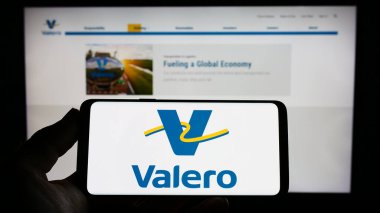 Stuttgart, Almanya - 04-16-2023: ABD 'li petrol şirketi Valero Energy Corporation' ın logosunu elinde tutan kişi web sitesinin önünde ekranda. Telefon ekranına odaklan.