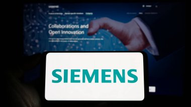 Stuttgart, Almanya - 04-16-2023: Alman holdingi Siemens AG 'nin logosunun bulunduğu akıllı telefonu web sitesinin önünde tutan kişi. Telefon ekranına odaklan.