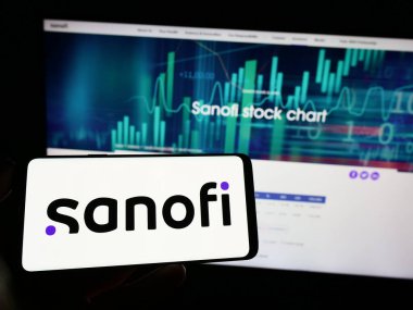 Stuttgart, Almanya - 04-16-2023: Fransız ilaç şirketi Sanofi SA 'nın logosunun bulunduğu cep telefonu sahibi kişi iş sayfasının önünde ekranda. Telefon ekranına odaklan.