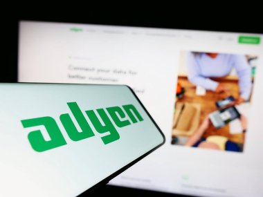 Stuttgart, Almanya - 04-16-2023: Hollandalı ödeme şirketi Adyen N.V. 'nin logosuna sahip akıllı telefon iş dünyasının web sitesinin önünde ekranda. Telefon ekranının merkezine odaklan.