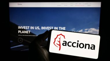 Stuttgart, Almanya - 04-16-2023: İnternet sitesinin önünde ekranda İspanyol altyapı şirketi Acciona S.A. 'nın logosunu taşıyan kişi. Telefon ekranına odaklan.