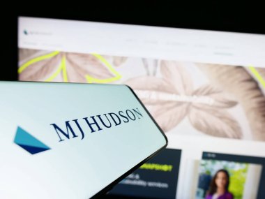 Stuttgart, Almanya - 04-19-2023: İngiliz finans şirketi MJ Hudson Group 'un logosunun yer aldığı cep telefonu web sitesinin önünde ekranda. Telefon ekranının merkez sağına odaklan.