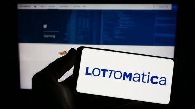 Stuttgart, Almanya - 04-19-2023: İtalyan kumar şirketi Lottomatica S.P.A. 'nın logosunu elinde tutan kişi web sitesinin önünde ekranda. Telefon ekranına odaklan.