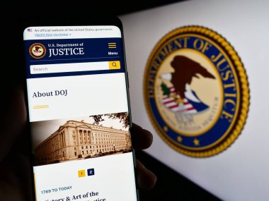 Stuttgart, Almanya - 04-19-2023: ABD Adalet Bakanlığı 'nın (DOJ) web sitesi ile cep telefonunu mühürlü ekranda tutan kişi. Telefon ekranının merkezine odaklan.