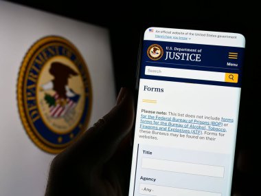 Stuttgart, Almanya - 04-19-2023: ABD Adalet Bakanlığı 'nın (DOJ) web sayfası bulunan cep telefonu logosu önünde ekranda. Telefon ekranının merkezine odaklan.