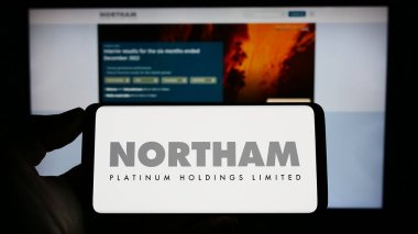 Stuttgart, Germany - 04-19-2023: Person holding cellphone with logo of company Northam Platinum Holdings Limited on screen in front of business webpage. Focus on phone display. clipart