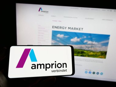 Stuttgart, Almanya - 04-20-2023: Alman TSO şirketi Amprion GmbH 'nin logosuna sahip cep telefonu sahibi kişi iş sayfasının önünde ekranda. Telefon ekranına odaklan.