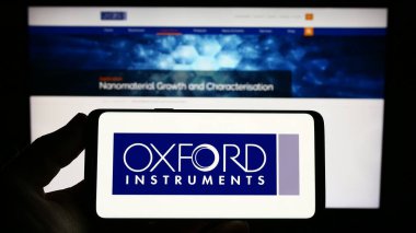 Stuttgart, Almanya - 04-20-2023: İngiliz Oxford Instruments plc şirketinin logosuna sahip kişi web sitesinin önünde ekranda. Telefon ekranına odaklan.