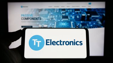 Stuttgart, Almanya - 04-20-2023: İngiliz şirketi TT Electronics plc 'in logosuna sahip akıllı telefon sahibi kişi web sitesinin önünde ekranda. Telefon ekranına odaklan.
