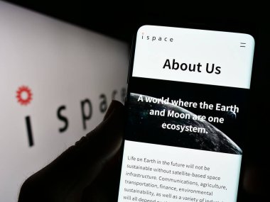 Stuttgart, Germany - 04-21-2023: Person holding cellphone with webpage of Japanese aerospace company ispace Inc. on screen in front of logo. Focus on center of phone display. clipart