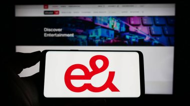 Stuttgart, Almanya - 04-23-2023: İnternet sitesi önünde Emirates Telekomünikasyon Grubu 'nun (etisalat) logosuna sahip akıllı telefonu elinde tutan kişi. Telefon ekranına odaklan.