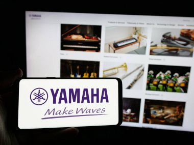 Stuttgart, Almanya - 01-09-2025: Japon ses donanım şirketi Yamaha Corporation 'ın logosunu elinde tutan kişi web sitesinin önünde ekranda. Telefon ekranına odaklan.