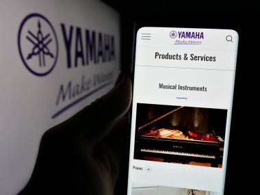 Stuttgart, Almanya - 01-09-2025: Japon ses donanım şirketi Yamaha Corporation 'ın web sayfası ile logolu cep telefonu tutan kişi. Telefon ekranının merkezine odaklan.