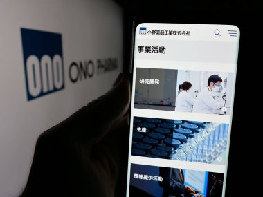 Stuttgart, Almanya - 01-14-2025: Japon şirketi Ono Pharmaceutical Co. Ltd. nin internet sayfası ile cep telefonu tutan kişi logonun önünde ekranda. Telefon ekranının merkezine odaklan.