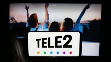 Stuttgart, Almanya - 01-14-2025: İsveçli telekomünikasyon şirketi Tele2 AB 'nin logosuyla cep telefonu sahibi kişi iş sayfasının önünde ekranda. Telefon ekranına odaklan.