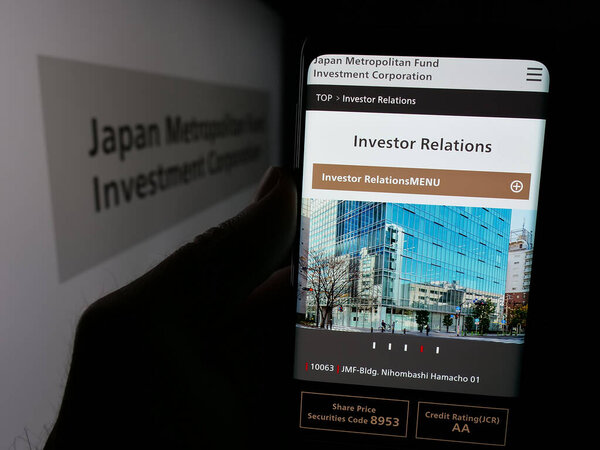 Stuttgart, Germany - 01-14-2025: Person holding smartphone with webpage of Japan Metropolitan Fund Investment Corporation (JMF) on screen with logo. Focus on center of phone display.