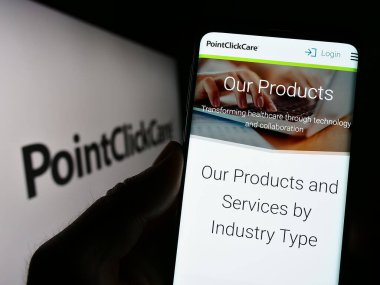 Stuttgart, Almanya - 03-30-2023: ABD 'li sağlık yazılım şirketi PointClickCare' in web sayfası ile akıllı telefon sahibi kişi logolu ekranda. Telefon ekranının merkezine odaklan.