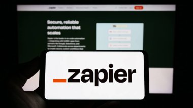 Stuttgart, Almanya - 03-30-2023: ABD 'li otomasyon yazılım şirketi Zapier Inc.' in logosuyla cep telefonu sahibi olan kişi iş sayfasının önünde ekranda. Telefon ekranına odaklan.