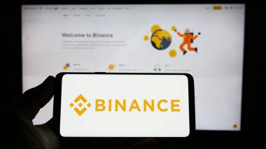 Stuttgart, Almanya - 03-31-2023: İnternet sitesi önünde ekranda şifreli takas şirketi Binance Holding Ltd. 'nin logosuna sahip akıllı telefonu tutan kişi. Telefon ekranına odaklan.