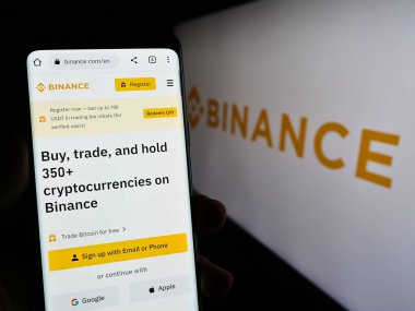 Stuttgart, Almanya - 03-31-2023: Kripto Değişim Şirketi Binance Holding Ltd. 'nin web sayfası ile cep telefonunu ekranda logoyla tutan kişi. Telefon ekranının merkezine odaklan.