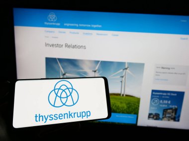 Stuttgart, Almanya - 03-31-2023: Alman holdingi ThyssenKrupp AG 'nin logosunun bulunduğu cep telefonu sahibi kişi iş sayfasının önünde ekranda. Telefon ekranına odaklan.