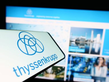 Stuttgart, Germany - 03-31-2023: Mobile phone with logo of German conglomerate ThyssenKrupp AG on screen in front of company website. Focus on center-right of phone display. clipart