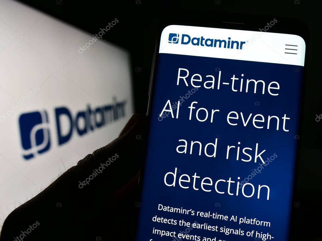 Stuttgart, Germany - 03-28-2023: Person holding celphone with website of artificial intelligence company Dataminr Inc. on screen with logo. Focus on center of phone display.