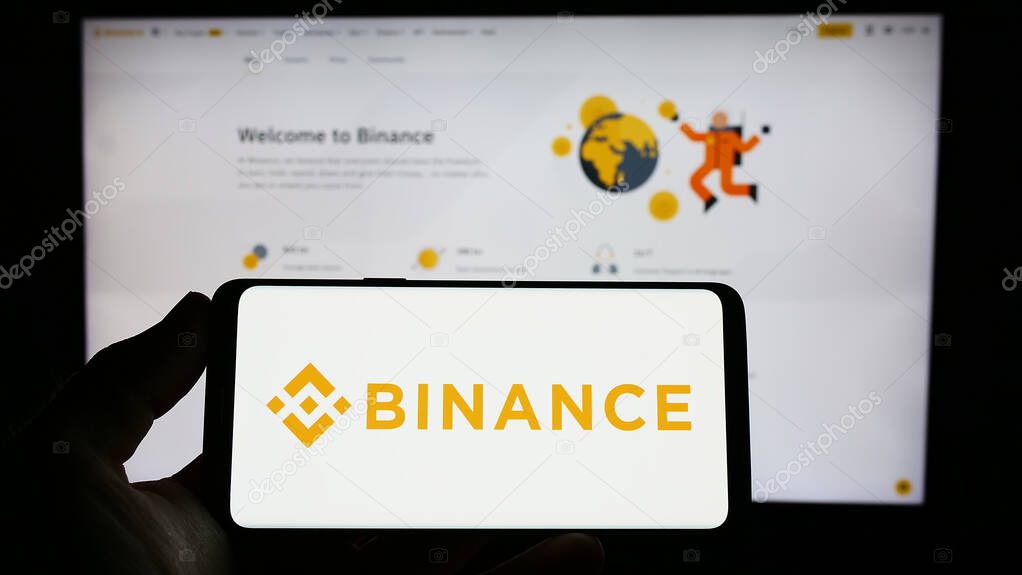 Stuttgart, Germany - 03-31-2023: Person holding smartphone with logo of crypto exchange company Binance Holdings Ltd. on screen in front of website. Focus on phone display.