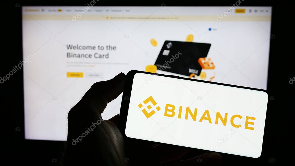 Stuttgart, Germany - 03-31-2023: Person holding mobile phone with logo of crypto exchange company Binance Holdings Ltd. on screen in front of web page. Focus on phone display.