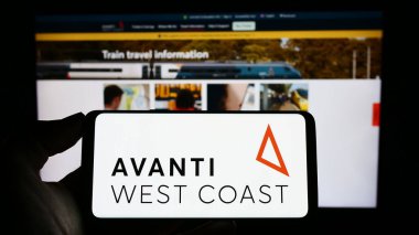 Stuttgart, Almanya - 03-31-2023: İngiliz tren şirketi Avanti West Coast 'un logosuyla cep telefonu sahibi kişi iş sayfasının önünde ekranda. Telefon ekranına odaklan.